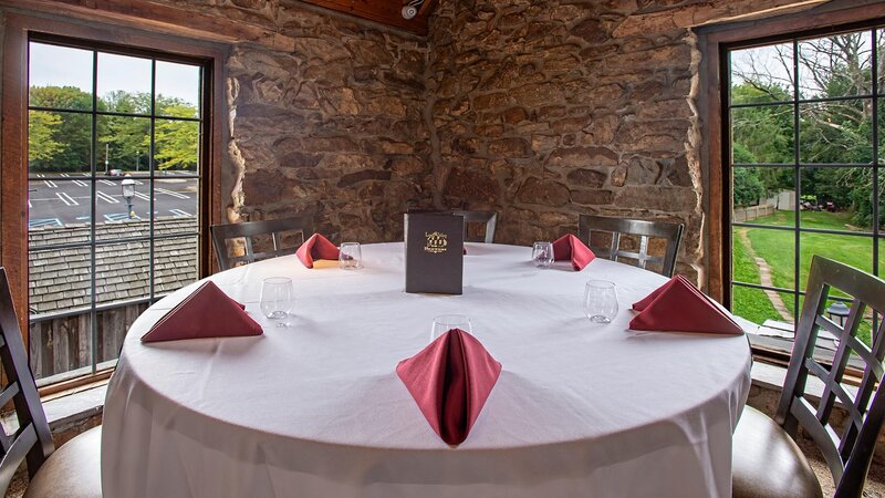 Round table with white table cloth with place settings for five guests